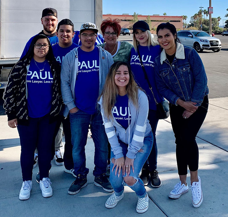 A diverse team of personal injury lawyers and staff from a Las Vegas law firm wearing branded shirts, posing outdoors with smiles and confidence.