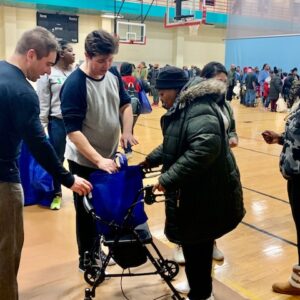 A Las Vegas personal injury law firm supports the community by helping a woman with a walker and other locals in a gymnasium, highlighting community involvement and support for those in need.