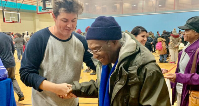 A photo depicts a Las Vegas law firm representative shaking hands with an elderly man at a community event, symbolizing their commitment to helping individuals with personal injury cases and supporting the local community.