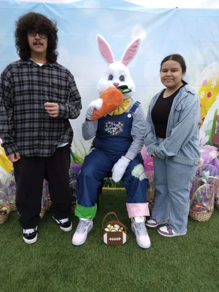 Las Vegas Easter event with a person dressed as the Easter bunny sitting with attendees, surrounded by Easter baskets, suggesting a family-friendly community event, possibly related to legal outreach.