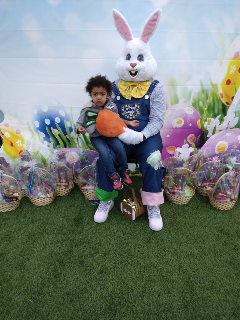 A child sits on the Easter Bunny's lap, surrounded by Easter baskets at a Las Vegas personal injury law firm event.