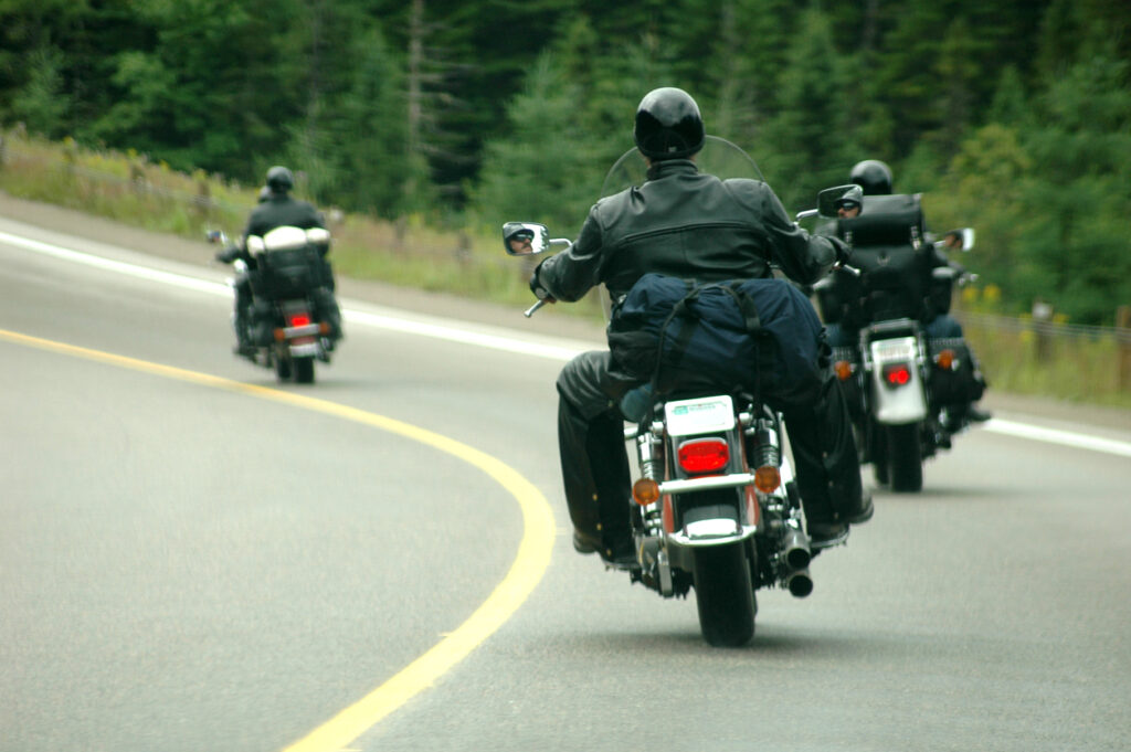 Three motorcyclists ride on a winding road, depicting the potential dangers and need for personal injury legal assistance after a motorcycle accident.