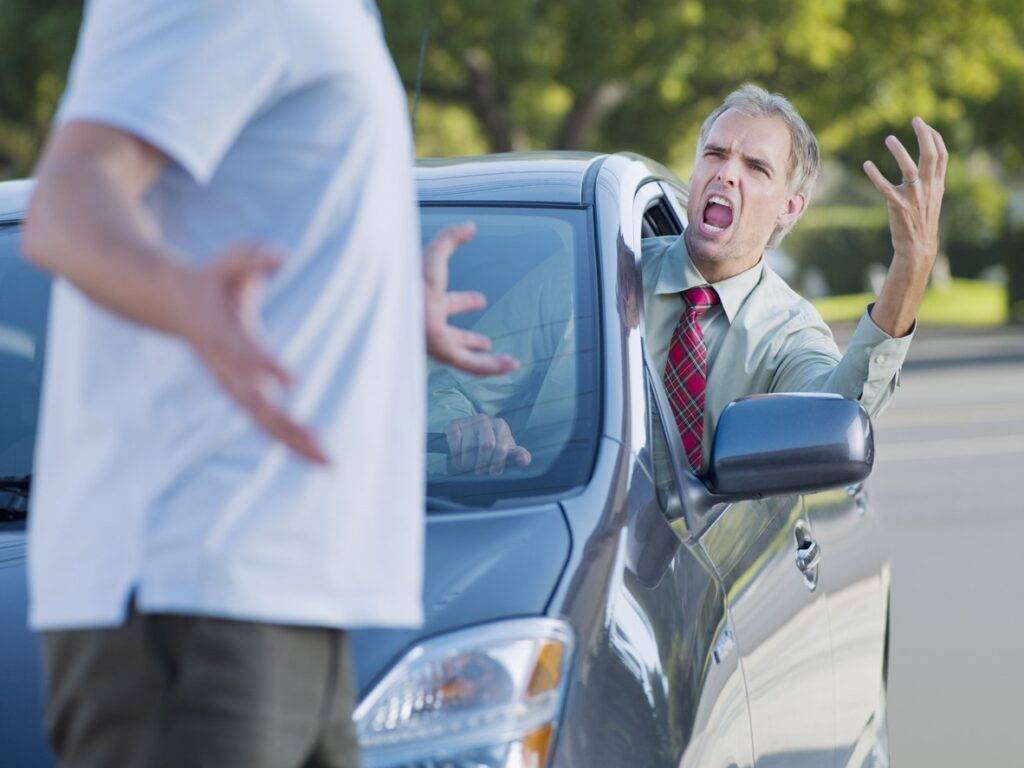 Angry driver shouting at a pedestrian blocking the road, illustrating road rage and aggressive driving behaviors 