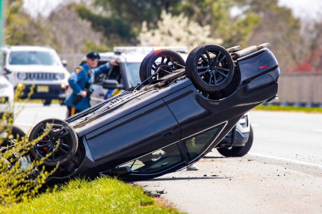 Vehicle rollover caused by aggressive driving on a highway, with police vehicles at the scene responding to the road rage incident 