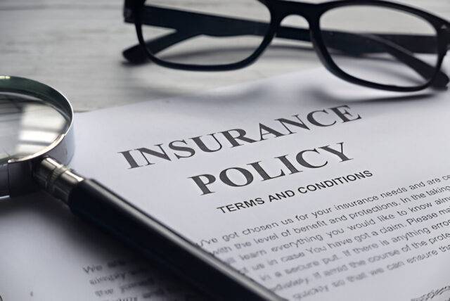 Close-up of an insurance policy document with a magnifying glass and glasses, representing the detailed investigation and legal expertise provided by a Las Vegas law firm specializing in personal injury claims.